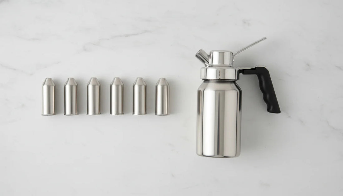 Multiple N2O whipped cream dispenser cartridges lined up beside a stainless steel dispenser
